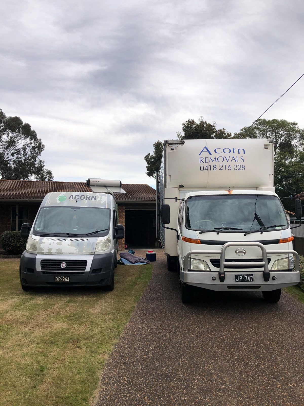 The Acorn Furniture Removals fleet at the Lake Munmorah depot — branded trucks across two generations of the business